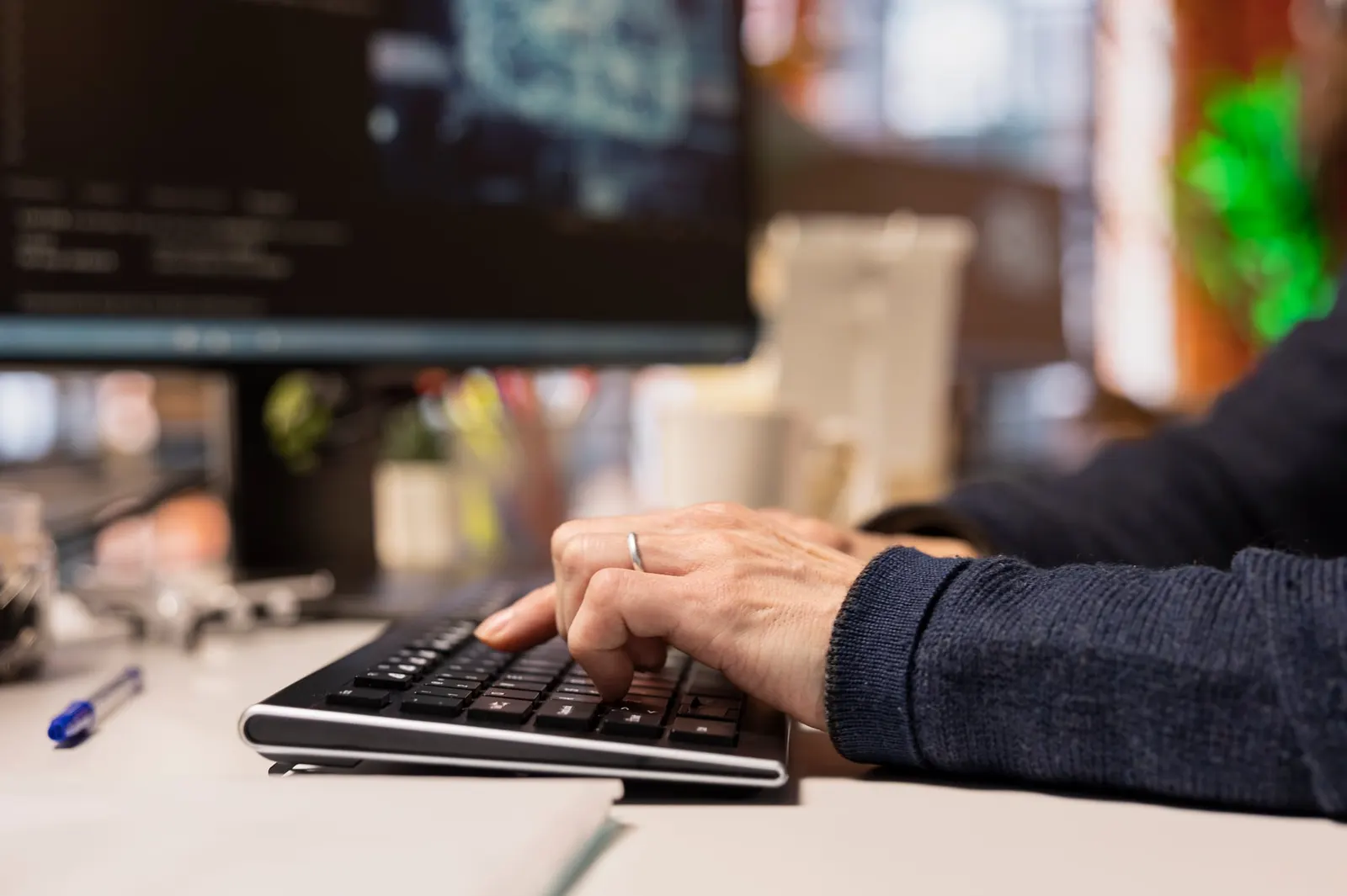 Manos de un desarrollador escribiendo en un teclado frente a la pantalla